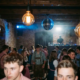 Münchner Bar verwandelt sich in Tanzfläche mit Oktoberfest-Gästen unter Edison-Glühbirnen und Discokugel.