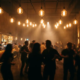Tanzende Silhouetten in einem Münchner Club, beleuchtet von warmem Glühlampenlicht und atmosphärischem Dunst über der Menge.