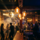 Belebte Bar mit Discokugel, Edison-Glühbirnen in Bernsteinlicht und tanzenden Silhouetten in stimmungsvollem Nachtleben-Ambiente.