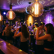 Tanzende Menschen in einer stimmungsvollen Bar mit Discokugel, Edison-Glühbirnen und warmem Licht auf Backsteinwänden.